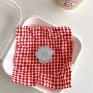 Detail of translucent cat paw phone grip with matte texture on red checkered fabric