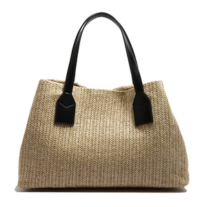 Handwoven straw tote bag with black faux leather handles for summer vacation