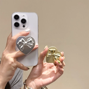 Dettaglio del supporto per telefono a cuore con rilievo a fiocco, finitura metallo