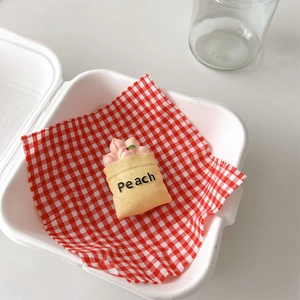 Macro detail of a cute peach fruit miniature bag stand on red checkered picnic paper