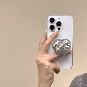 Dettaglio del supporto per telefono a cuore argentato con fiocco 3D su smartphone