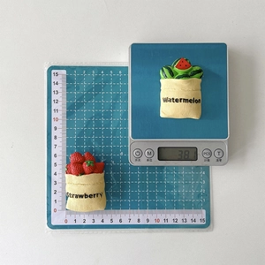 Detail view of 3D strawberry and watermelon phone grips showing 6cm size and 38g weight