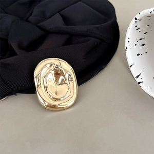 Détail d'un accessoire métallique doré à texture de lave sur une bande élastique noire