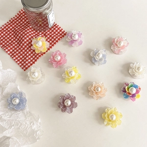 Flat lay of colorful flower phone grips with pearl centers on a white desk setting
