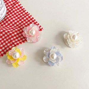 Detail of four colorful macaron pearl flower cell phone grips on a checkered cloth