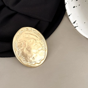Close-up of gold oval phone grip featuring an artistic water ripple metal texture