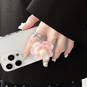 Detailed view of floral phone griptok with pink petals and central pearl on white phone
