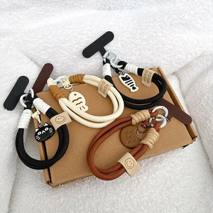 Handmade braided phone lanyards with cat and fishbone charms on sheepskin texture