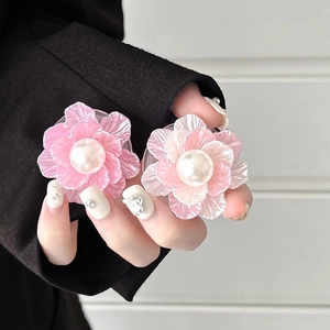 Detail of pink and cream floral phone grips with pearl centers held by a hand