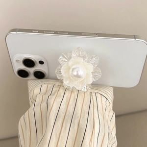 Close-up of a 3D resin flower phone grip with central pearl detail on white smartphone