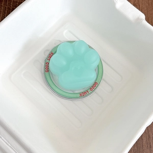 Macro shot of mint green 3D cat paw phone grip featuring Good Luck engraving detail
