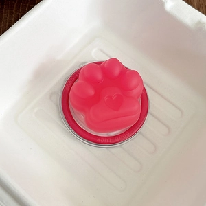 Macro shot of 3D pink cat paw magnetic phone grip with heart detail on a red base