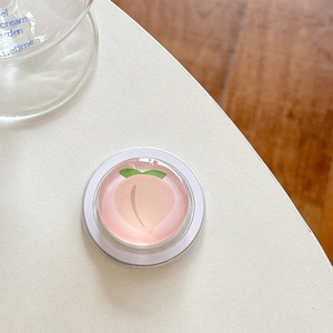 Close-up of a cute 3D glossy peach design expandable cell phone grip on a white surface