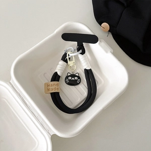 Close-up of black and white braided rope lanyard with cartoon cat charm and handmade tag