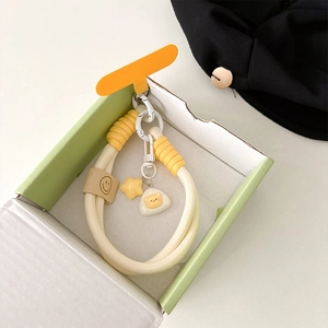 Detail of woven phone strap with cartoon charms and yellow star in gift box