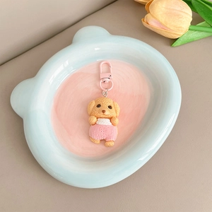Détail d'un pendentif chiot mignon avec chemise rayée rose dans une assiette ours bleue