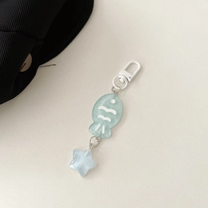 Detail of green resin fish and star pendant charms with white hardware for bags