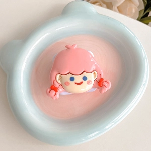 Close-up of cute cartoon girl phone socket stand on blue ceramic tray decoration