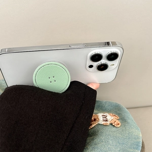 Detail of light green leather textured round phone grip socket on a white smartphone