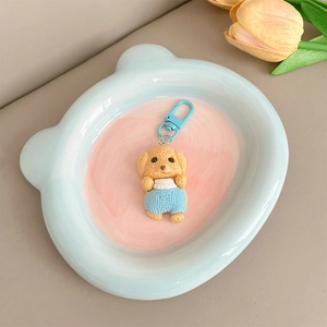 Gros plan d'un pendentif chiot mignon avec un crochet bleu sur un plateau décoratif