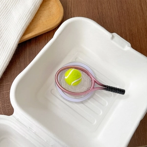 Detailed close-up of a mini tennis racket and ball phone grip on a round base