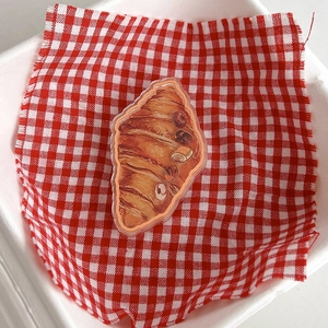 Close-up of realistic croissant acrylic phone grip on red and white checkered cloth
