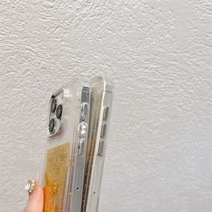 Close-up of clear iPhone case with gold foil flakes and traditional golden charms