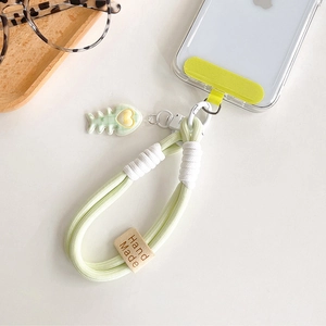 Close-up of handmade green woven phone strap with cute fish charm and leather tag