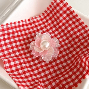 Detail of pink 3D flower phone socket with center pearl on red gingham background