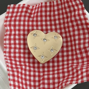 Dettaglio di un supporto per telefono a cuore dorato con stelle incise e strass
