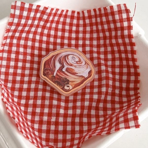 Macro detail of cinnamon roll acrylic phone grip on red and white checkered cloth
