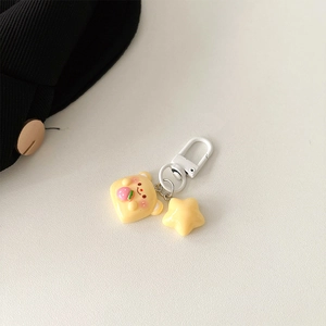 Detail of cute yellow resin bear and star charms on a white metal keychain clip