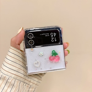 Détail de coque Galaxy Z Flip avec breloques cerise et cœur en perles sur fond pailleté