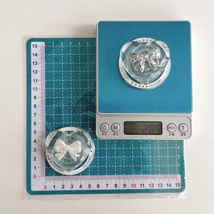 Transparent heart phone grip with silver bow accent, shown on scale for 28.5g weight