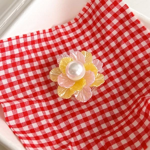 Close-up of pink and yellow floral phone socket with pearl center on plaid background