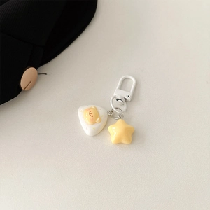 Detail of cute yellow bear and star pendants with white metal clip on textured background