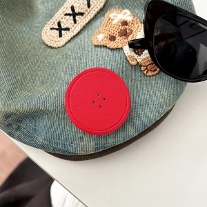 Detail of denim blue phone socket with cartoon bear embroidery and red button decoration