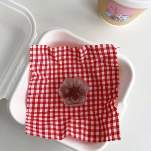 Detail of creative translucent cat paw phone grip resting on a red checkered cloth