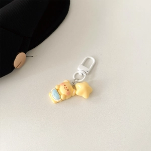 Close-up of yellow resin bear and star charms on a braided strap with white metal clip
