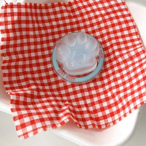 Detail of cute transparent cat paw phone socket with blue Good Luck base on plaid fabric