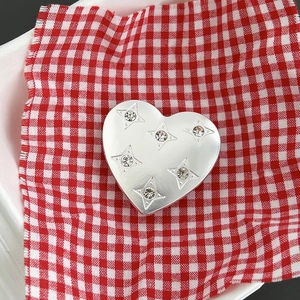 Dettaglio del supporto per telefono a cuore in argento con stelle incise e strass lucidi