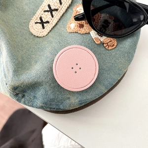 Macro view of blue denim hat with cute bear embroidery and pink decorative patch