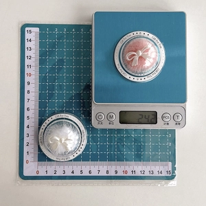 Detail view of pearl bow pompom phone grip showing 50mm diameter and 24.2g weight