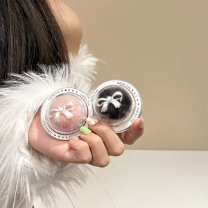 Detail of pink and black plush hair accessories with pearl bow in gift packaging