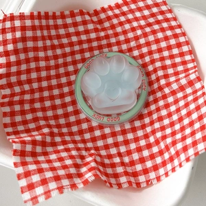 Macro shot of 3D cat paw phone stand with mint green Good Luck ring on checkered cloth