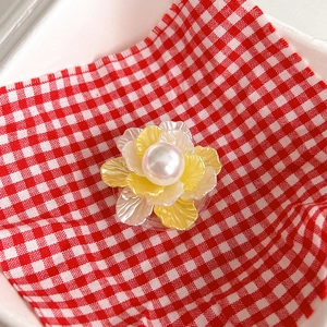 Detailed close-up of a flower-shaped phone grip with a large pearl center on plaid fabric