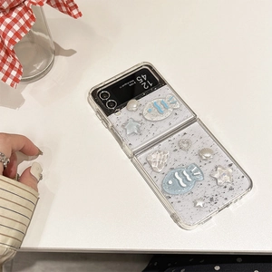 Dettaglio custodia Galaxy Z Flip trasparente con ciondoli oceanici come conchiglie e pesci