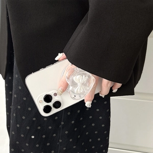 Detail of transparent heart-shaped phone grip with a 3D white bow tie on iPhone