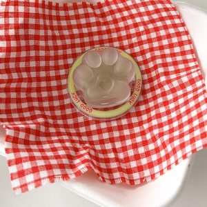 Close-up of translucent cat paw phone stand with heart relief on red plaid fabric