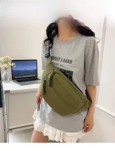 Detail of dark green nylon chest bag with plastic buckle and woven zipper pulls
